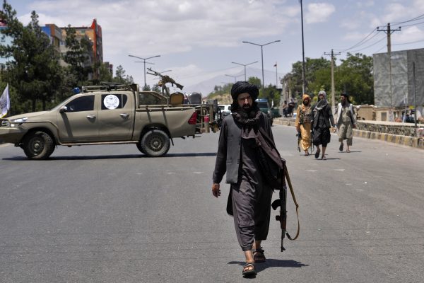 taliban fighter walking down street holding gun