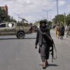 taliban fighter walking down street holding gun
